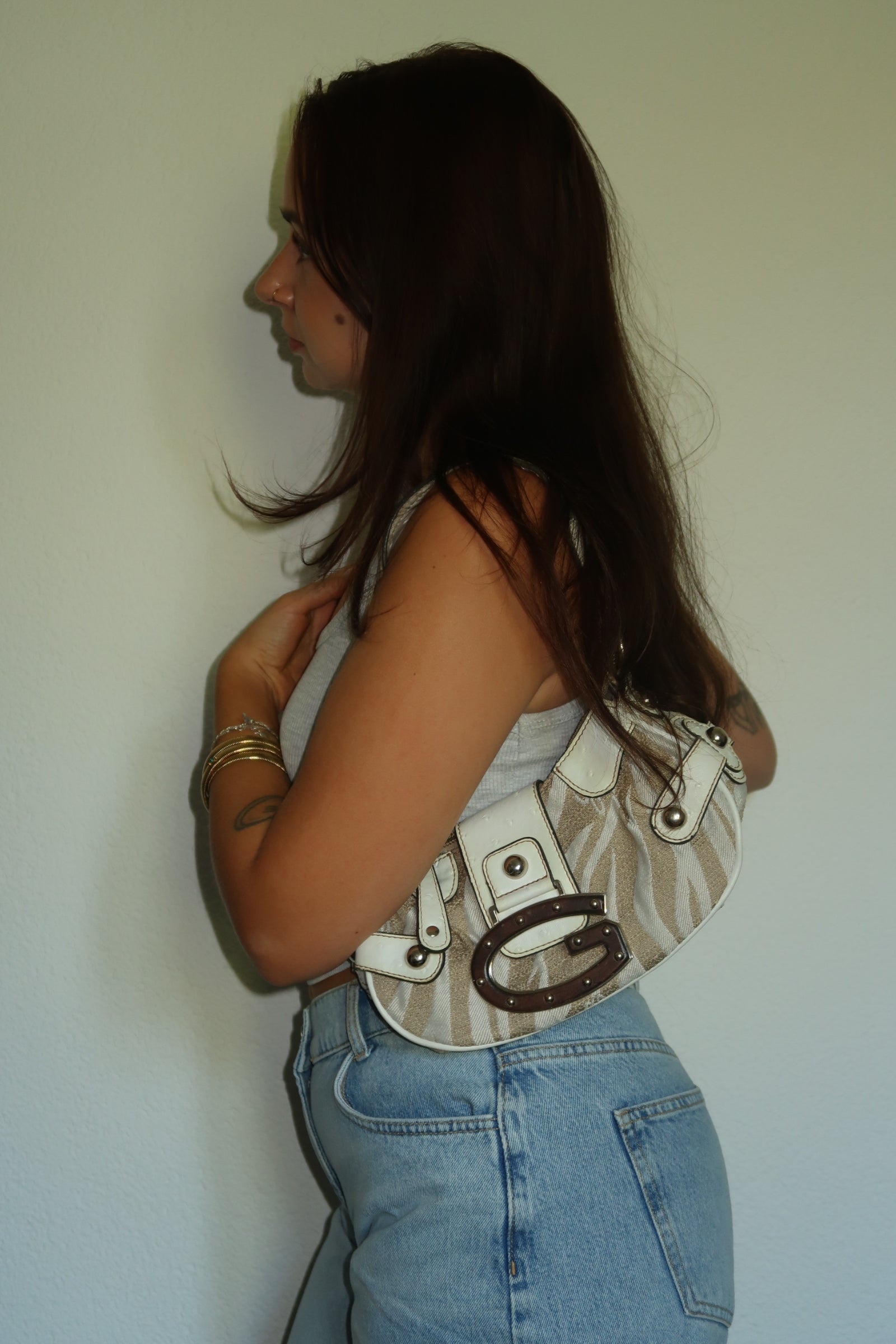Woman wearing a vintage Guess Y2K shoulder bag in beige.
