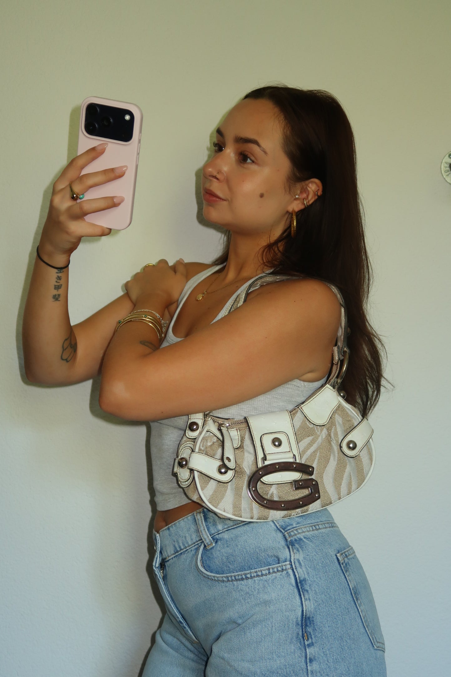 Woman wearing a vintage Guess Y2K shoulder bag in beige.
