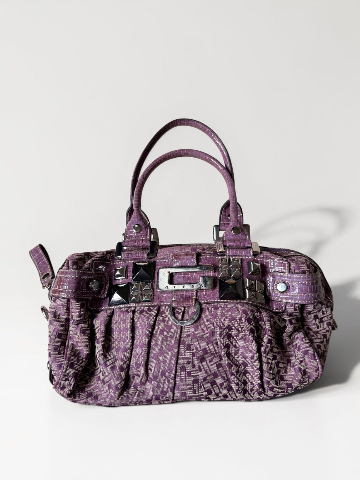 Lila Vintage Guess Handtasche mit Monogramm-Muster, Kroko-Details, silberfarbenen Nieten und Guess-Logo
