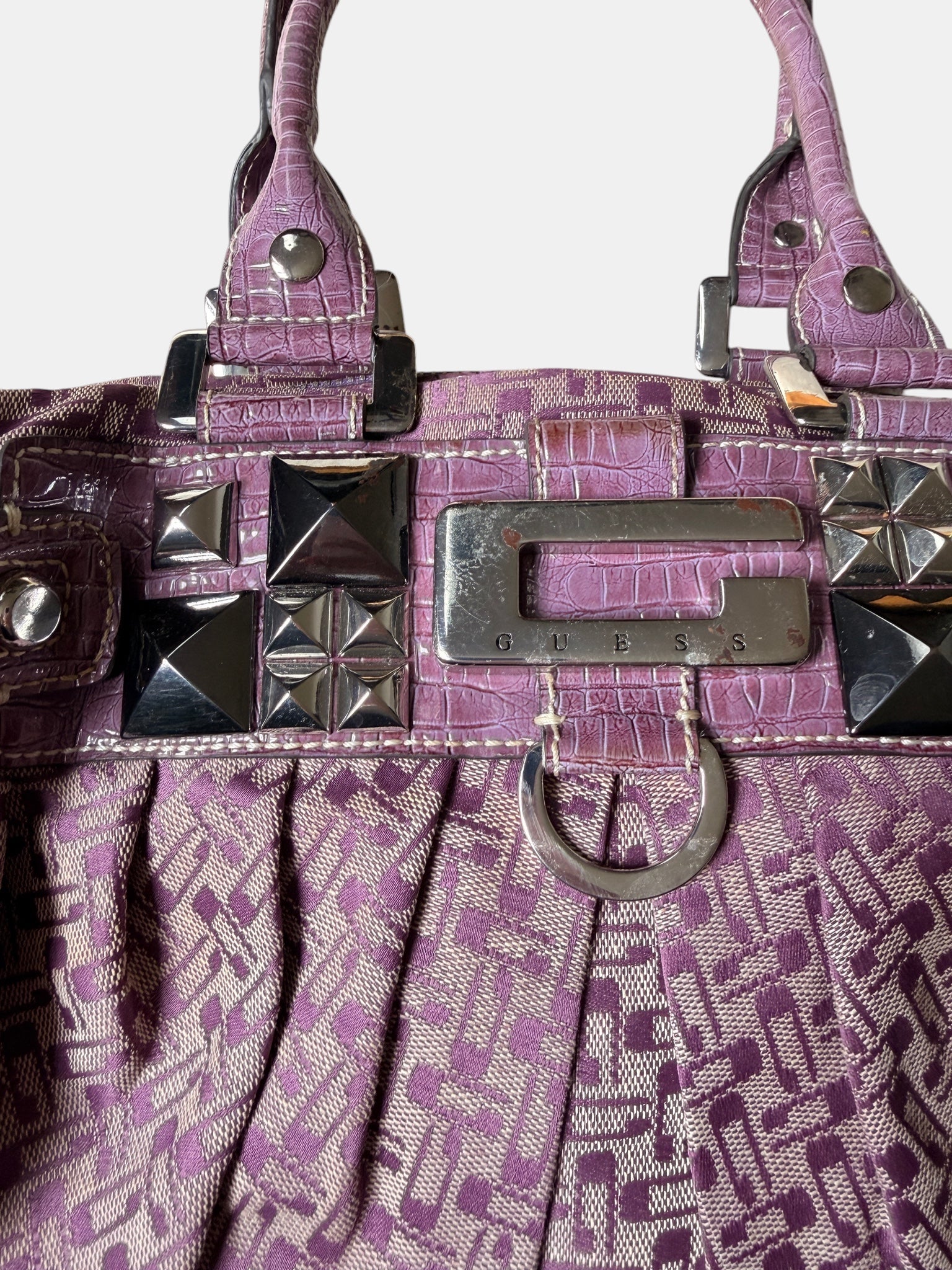 Lila Vintage Guess Handtasche mit Monogramm-Muster, Kroko-Details, silberfarbenen Nieten und Guess-Logo